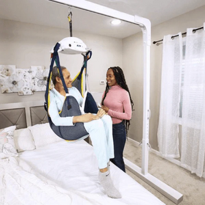 Woman being lifted onto the bed using the P-440 Portable Ceiling Patient Lift by Handicare | Wheelchair Liberty Blog